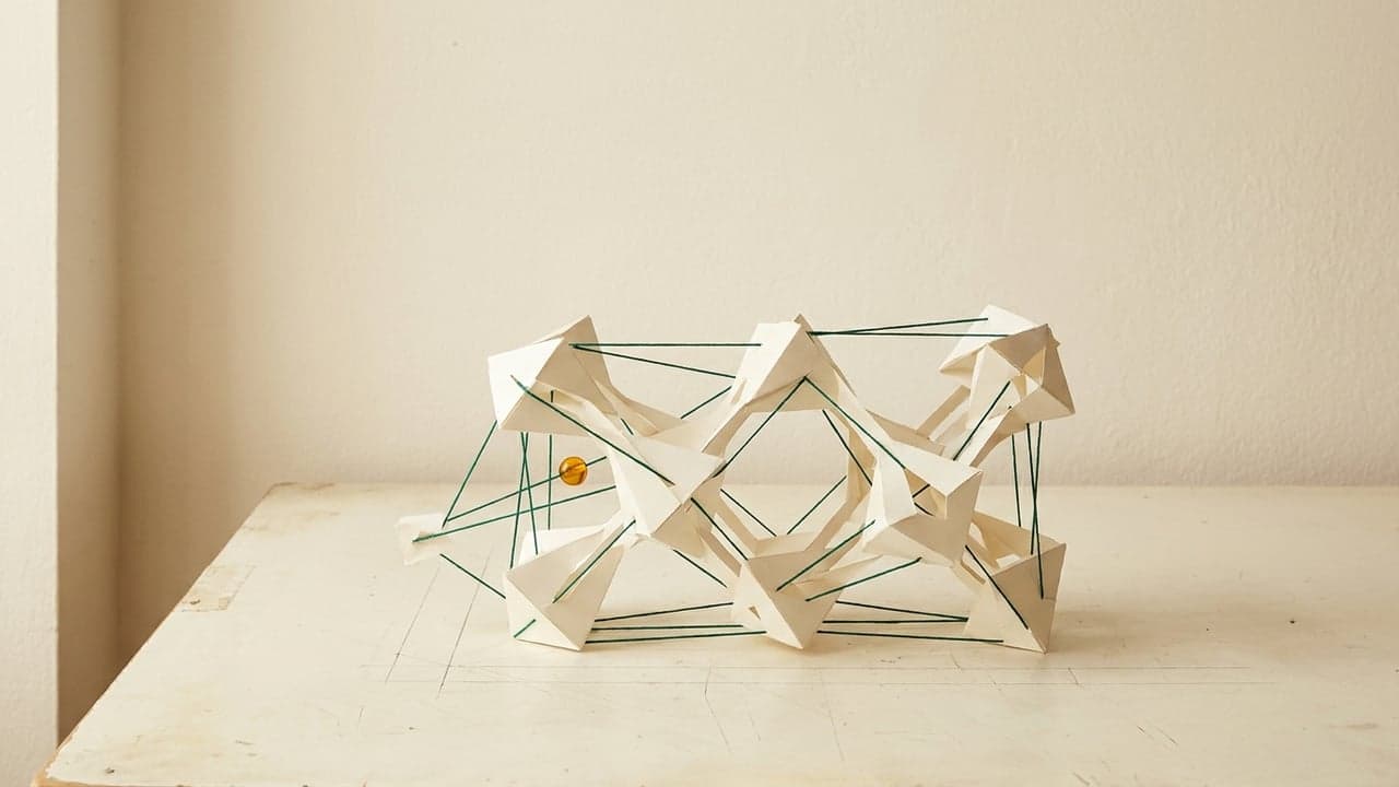 Módulos de papel conectados por hilos verdes sobre una mesa de dibujo